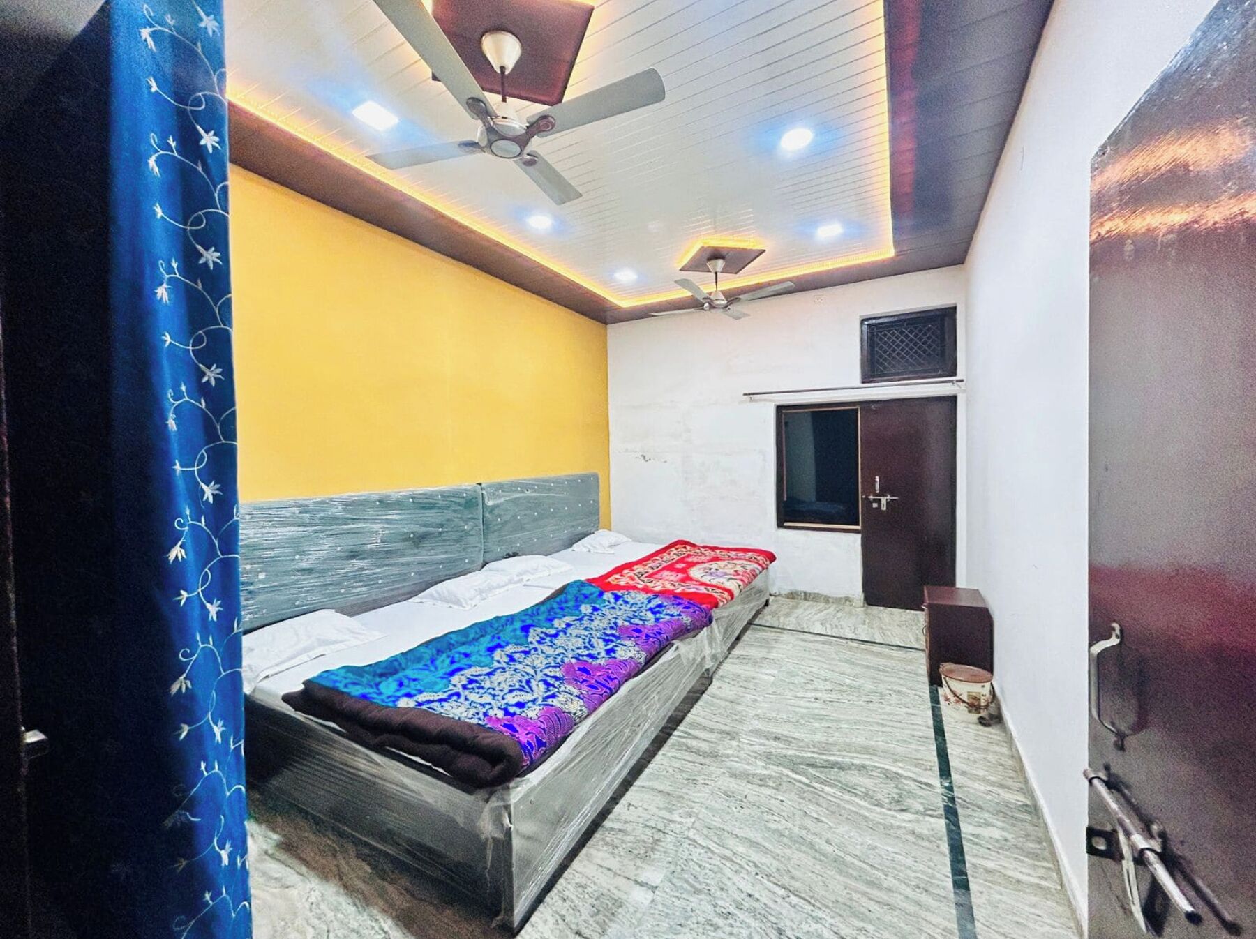 Un dormitorio con cama, ventilador de techo y ventana.