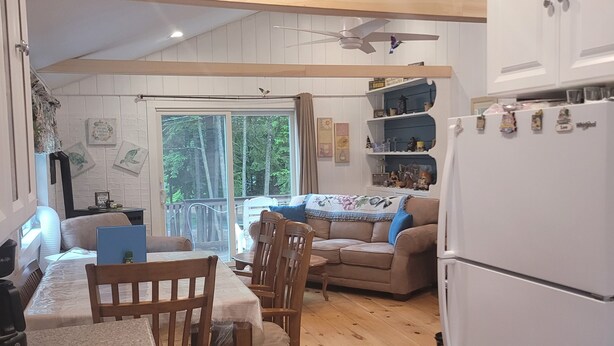A cozy kitchen with wooden floors, a dining table with chairs, a sofa, and a refrigerator. - Lakeside Lagoon W/ Kayaks & Beach Pass (Middleton)
