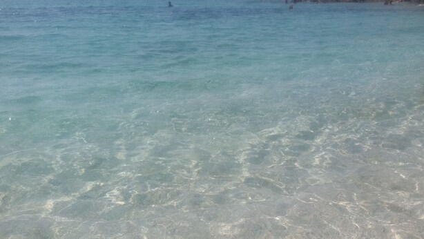 A clear view of a beach with shallow water and a rocky cliff. - Villa in Sardinia 5 minutes from the beach (Porto Torres)