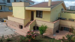 A two-story residential building with a flat roof, a small porch, and a staircase leading to the entrance. - Villa in Sardinia 5 minutes from the beach (Porto Torres)