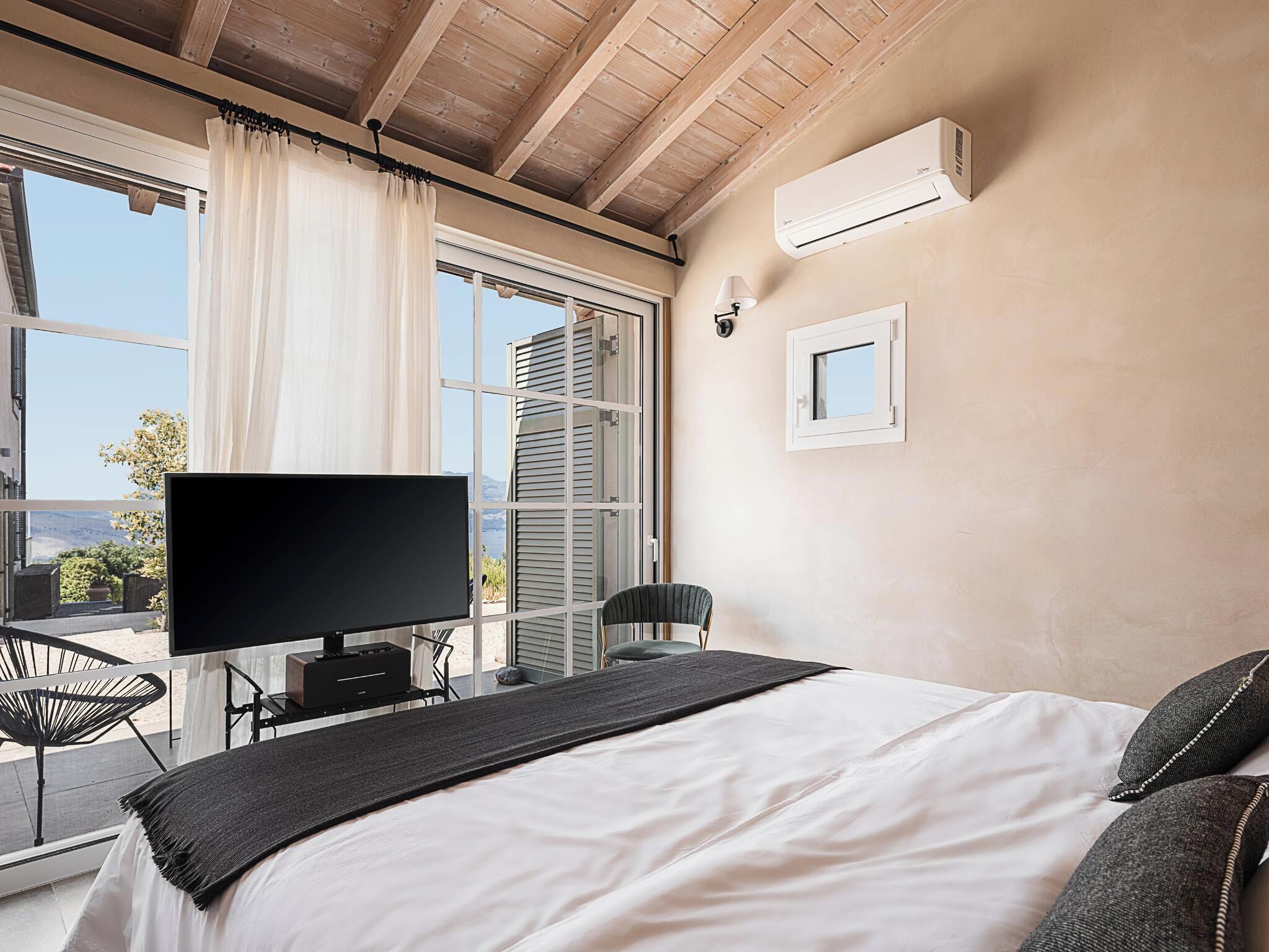 Una camera da letto con un letto grande, una televisione e vista sull'esterno attraverso una finestra.