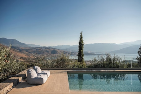 Una piscina al aire libre, sombrillas, sillones reclinables de piscina. Rosmarino Villa Galaxidi