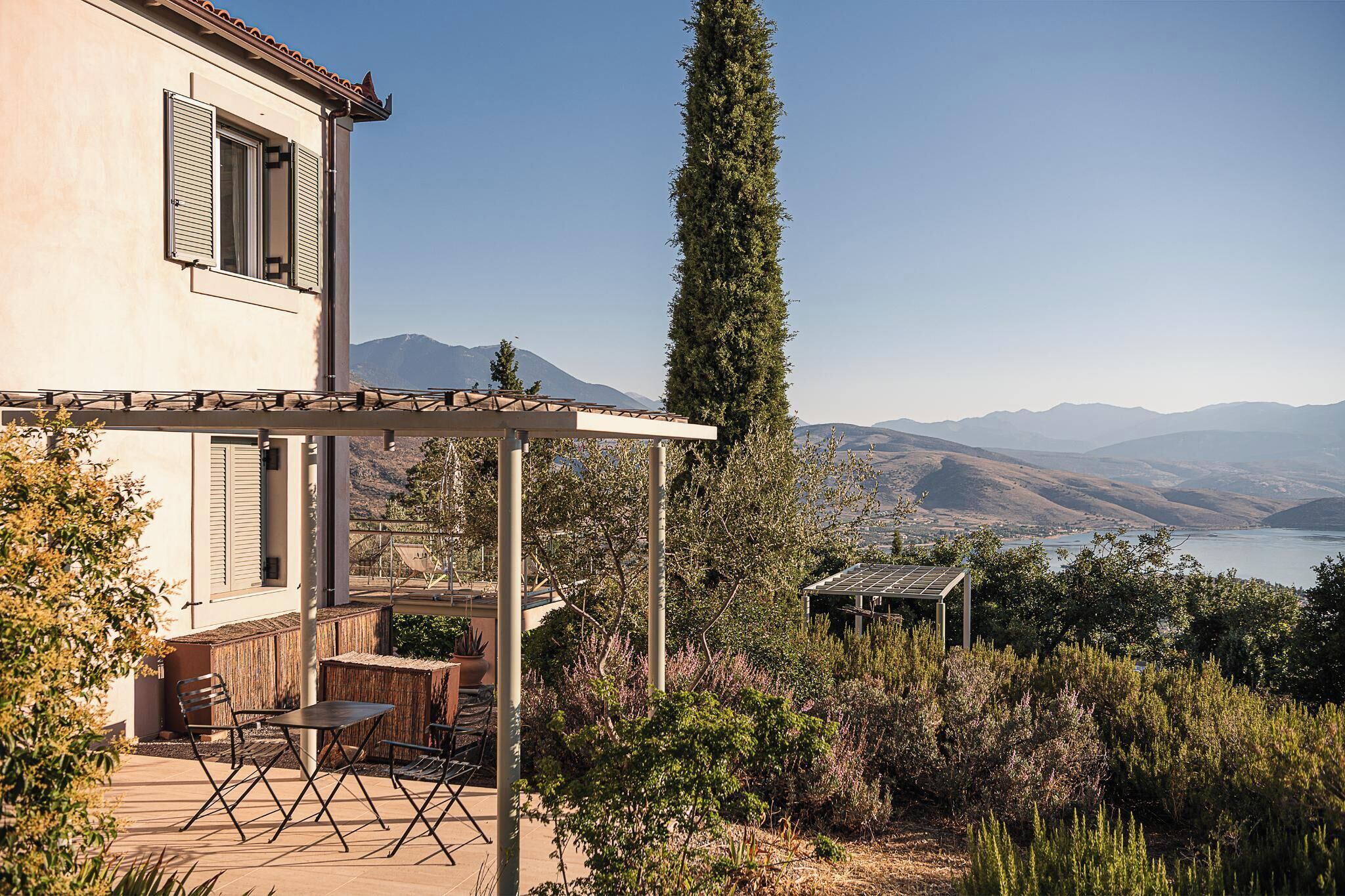 A house with a patio, outdoor seating, and a view of mountains and a lake.