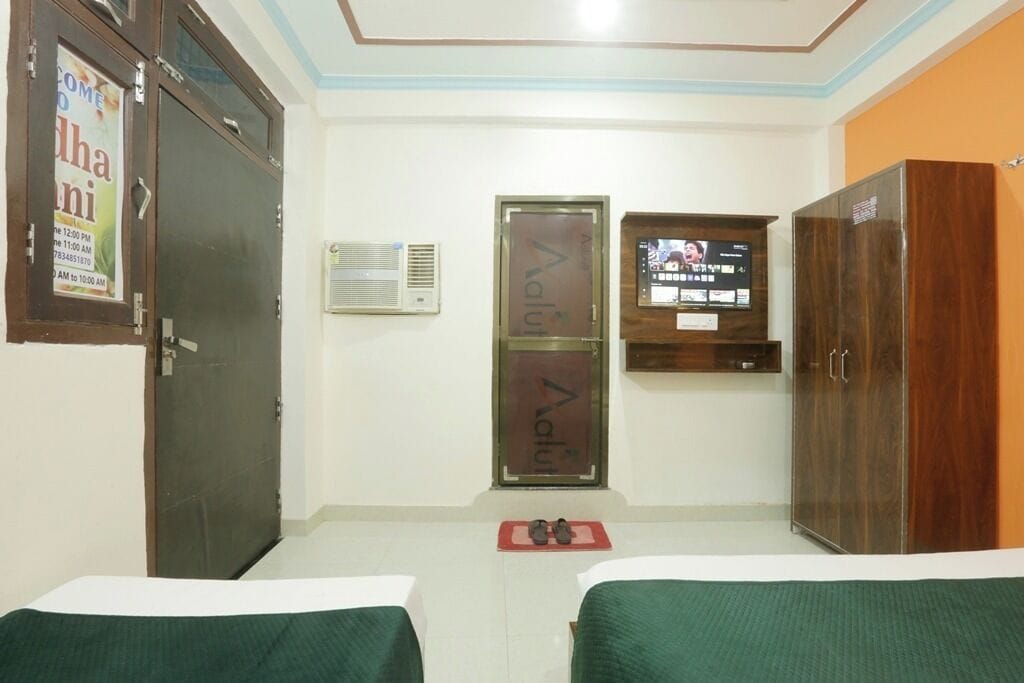 A hotel room with two beds, a TV, a wardrobe, and a door with a sign.