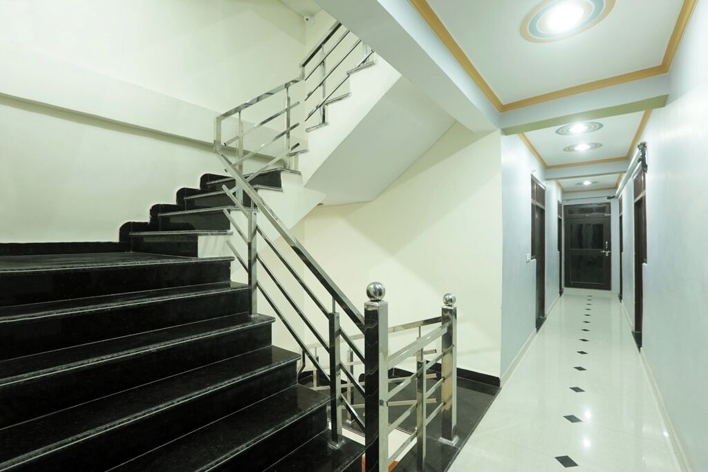 A modern staircase with black steps and metal railings, leading to a hallway with white walls and a tiled floor.
