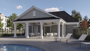 A covered patio with a pool, outdoor seating, and a view of a residential neighborhood.