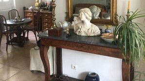 A dining area with a table, chairs, a lamp, a mirror, and a statue.