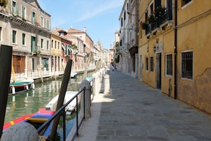 Un canal étroit, bordé de bâtiments historiques dotés de balcons et de fenêtres, avec des bateaux amarrés sur la rive gauche.