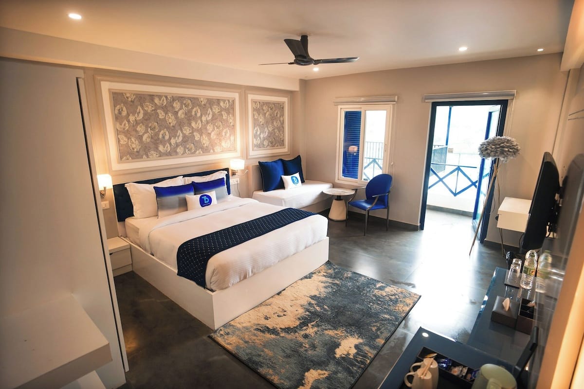 A modern hotel room with a large bed, a desk, and a balcony.