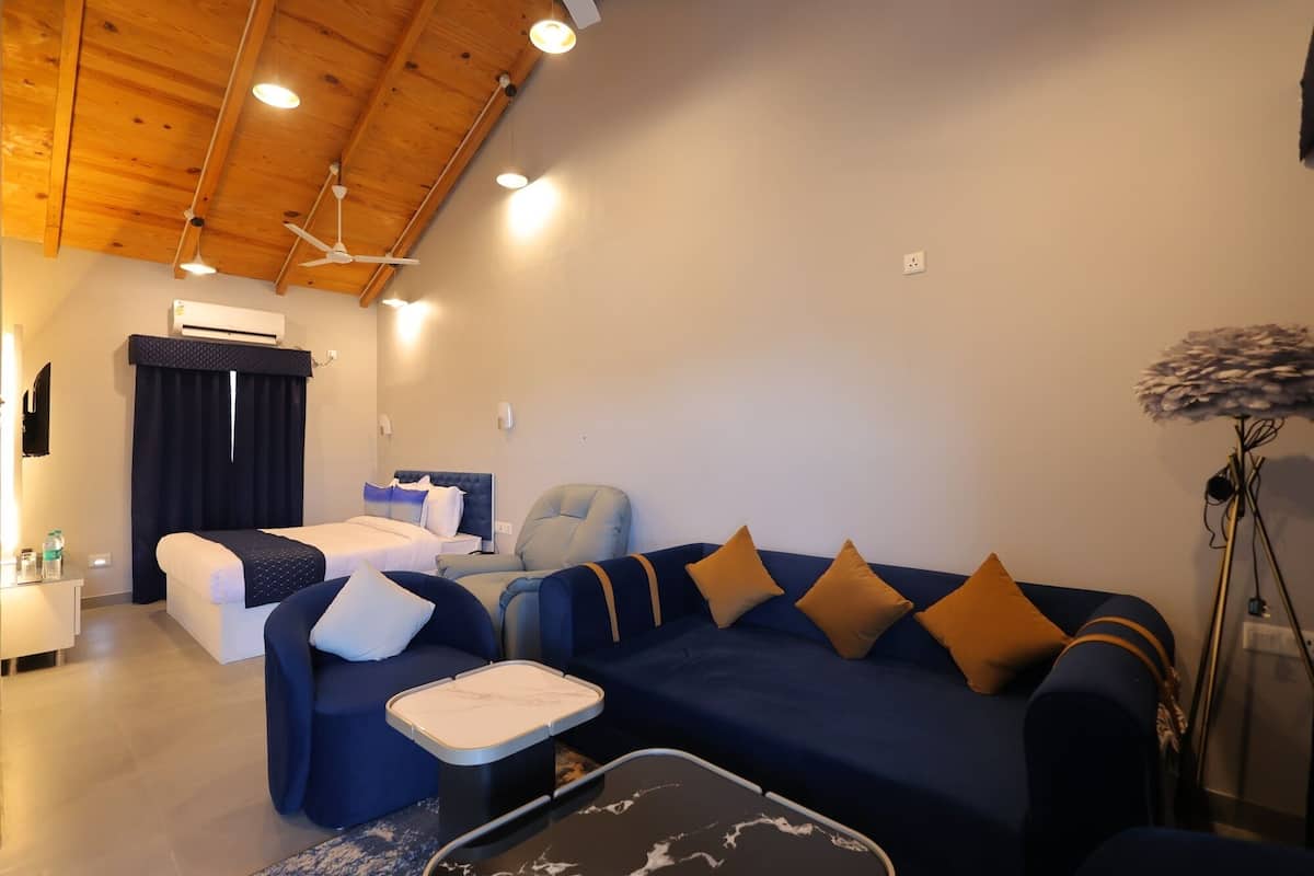 A modern living room with a blue sofa, a small coffee table, a ceiling fan, and a TV mounted on the wall.