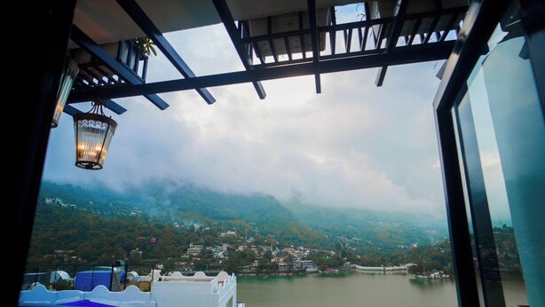 Vista desde un balcón sobre un lago, con edificios a lo lejos y un cielo nublado.