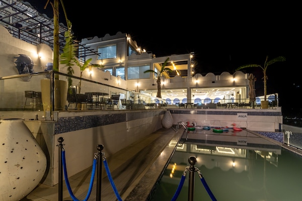 Una piscina al aire libre, sombrillas, sillones reclinables de piscina