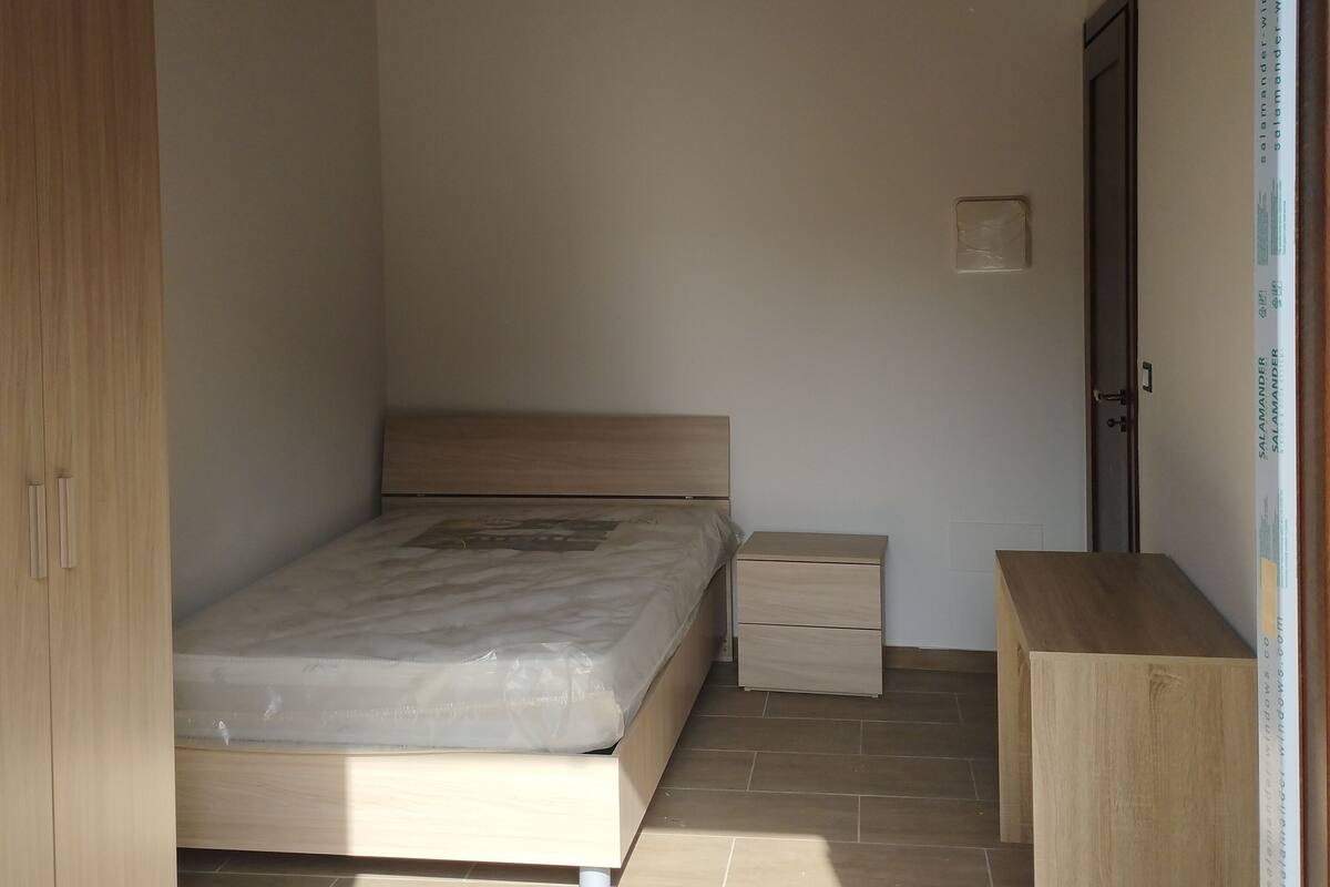 A bedroom with a bed, bedside table, and wardrobe.