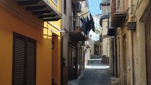 A narrow cobblestone street flanked by buildings with balconies and shutters. - Corleone bed and breakfast  (Corleone)