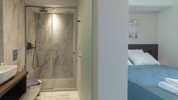A modern bathroom with a marble shower enclosure, a sink, and a toilet.