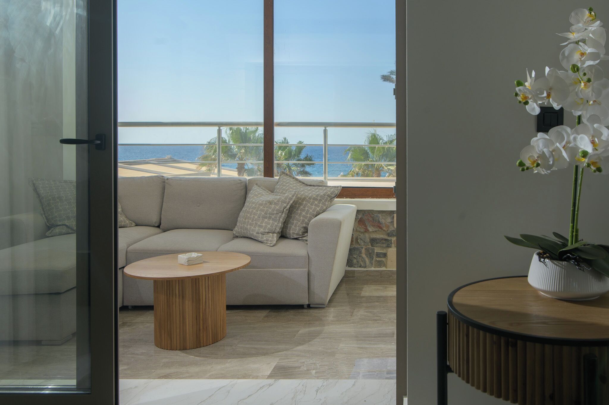 Uma sala de estar moderna com sofá, mesa de centro redonda e uma orquídea em vaso.