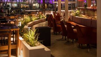 A modern bar area with seating and a view of the cityscape at night.