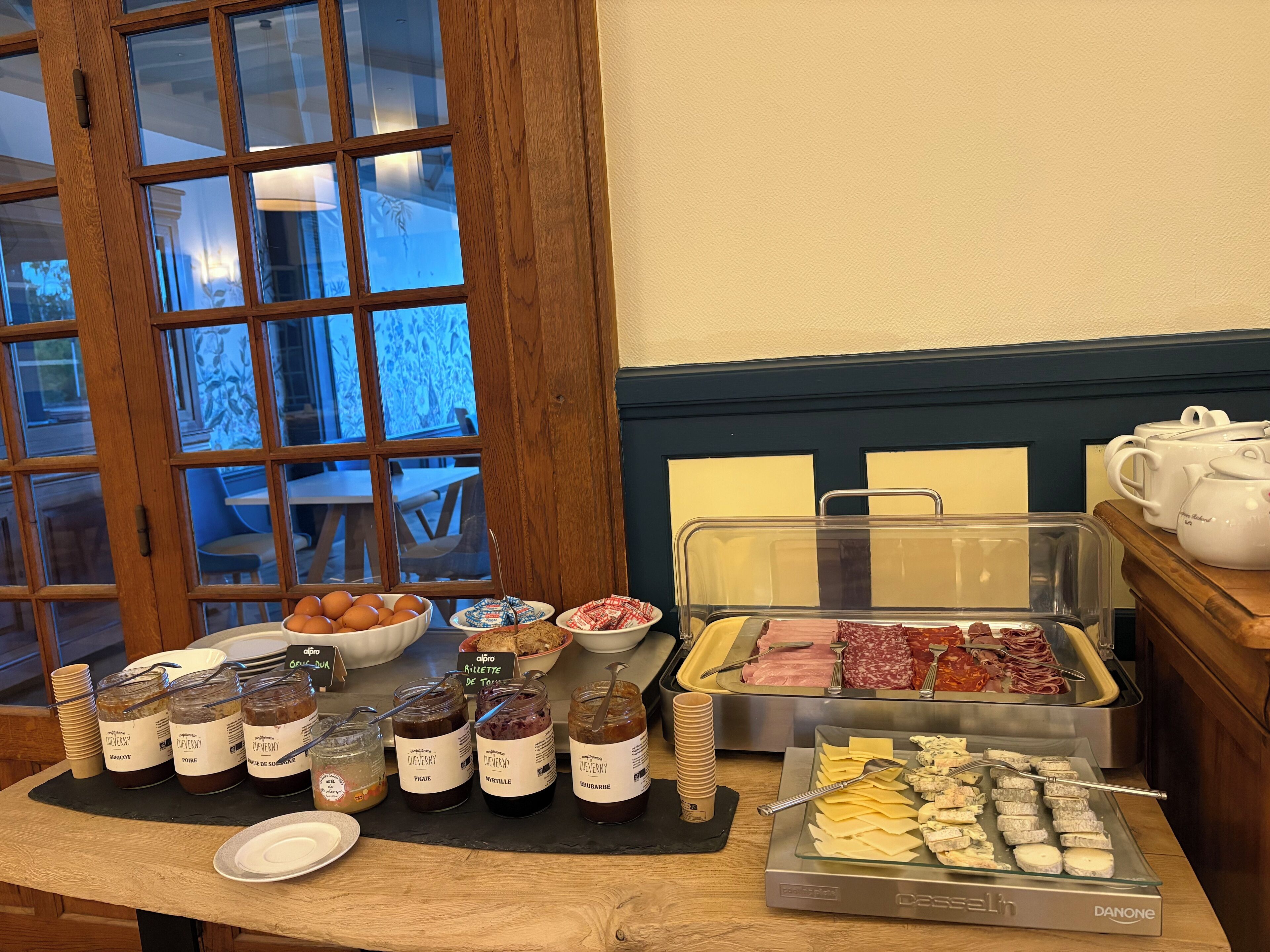 Ein reichhaltiges Buffet mit verschiedenen Speisen, darunter Gläser mit Marmelade, eine Auswahl an Fleischwaren und Käse.