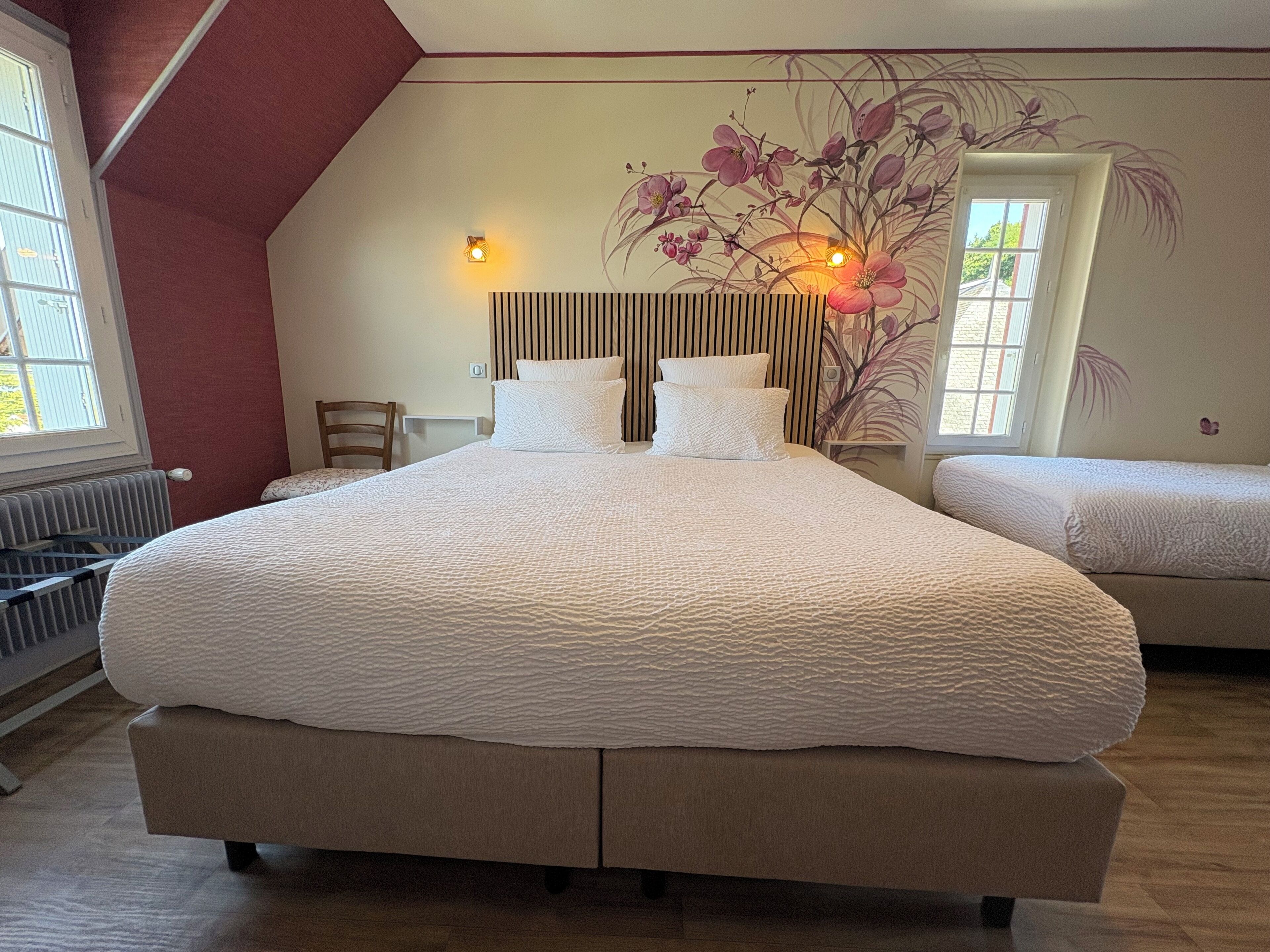 A bedroom with a large bed, a chair, a radiator, and a wall-mounted light fixture.