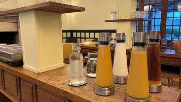 A bar area with various beverage dispensers and a shelf with glasses.
