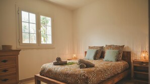 A bedroom with a wooden bed, a window, a bedside table, and a nightstand. - L'ESCAPADE DES HAUTS, spacious villa overlooking the Piton des Neiges. (Le Tampon)