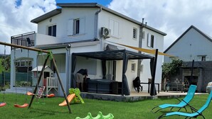 A residential property with a covered outdoor area, a swing set, and a lawn. - L'ESCAPADE DES HAUTS, spacious villa overlooking the Piton des Neiges. (Le Tampon)
