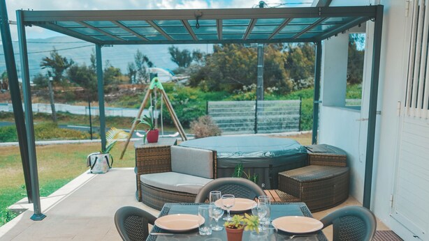 An outdoor patio with a table set for dining, surrounded by wicker furniture, under a shaded canopy. - L'ESCAPADE DES HAUTS, spacious villa overlooking the Piton des Neiges. (Le Tampon)