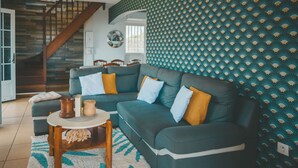 A living room with a sectional sofa, a coffee table, and a patterned wall. - L'ESCAPADE DES HAUTS, spacious villa overlooking the Piton des Neiges. (Le Tampon)