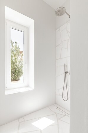 A modern bathroom with a shower, a window, and a view of greenery outside. - TWWO Antiparos (Antiparos)