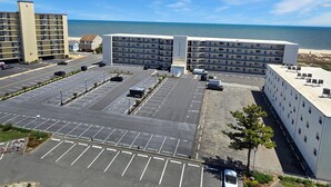 Ein mehrstöckiges Hotel mit Parkplatz vor der Tür, mit Blick auf einen Strand.