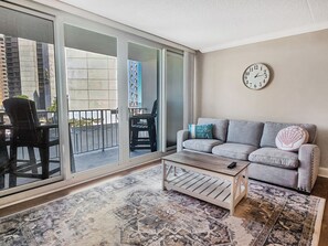 A living room with a grey sofa, a patterned rug, a wooden coffee table, and a wall clock.