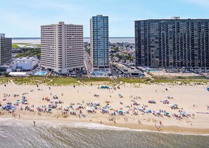 A beach with numerous umbrellas and people, surrounded by high-rise buildings. - Oceanfront 3rd Floor Condo with Pool just steps from the Atlantic Ocean! Quay #301 (Ocean City)