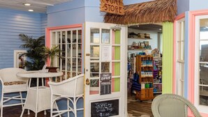A quaint store with a 'QUAY STORE' sign, wicker chairs, a small table, and a chalkboard sign advertising jewelry and gift bags. - Oceanfront 3rd Floor Condo with Pool just steps from the Atlantic Ocean! Quay #301 (Ocean City)