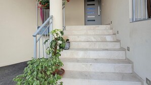 Una scala con corrimano, piante in vaso e una porta in cima.