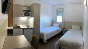 A compact hotel room with a kitchenette, a bed, and a window. - BE MYHOTEL (Évreux)