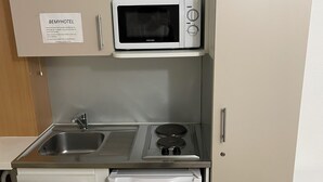 A compact kitchenette with a microwave, sink, and small refrigerator. - BE MYHOTEL (Évreux)