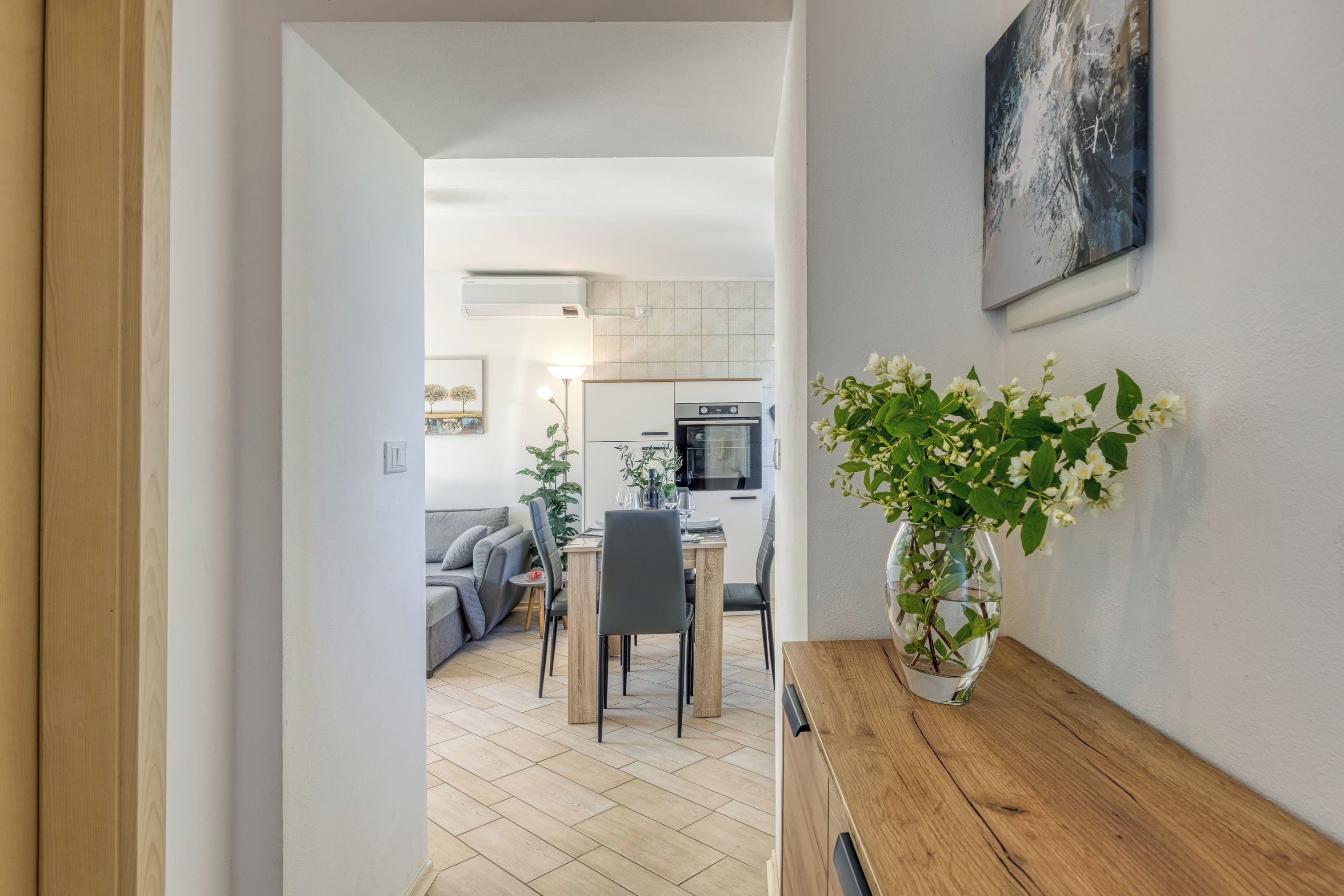 Una cucina moderna con zona pranzo, un tavolo di legno e un vaso con fiori.