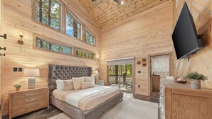 Un dormitorio con una cama grande, paredes de madera y un televisor montado en la pared.