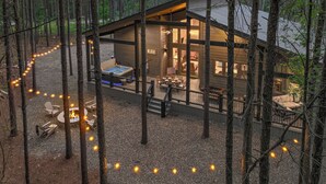 Una cabaña con terraza, un brasero y un jacuzzi.