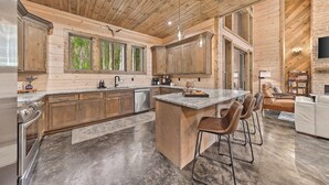 Una cocina amplia con armarios de madera, una isla grande con taburetes de bar y encimera de piedra.
