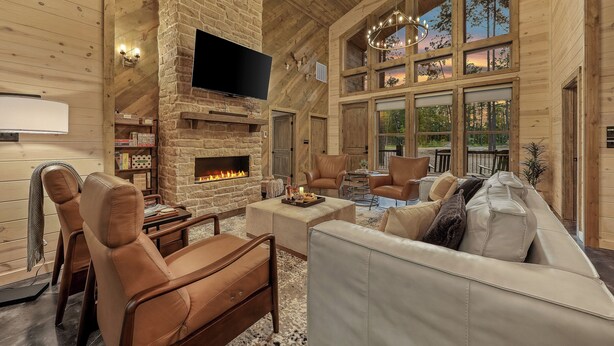 Amplia sala de estar con chimenea, sofás de cuero y un televisor grande.