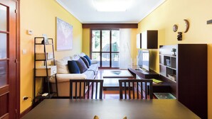 A living room with a sofa, coffee table, TV, and shelves.