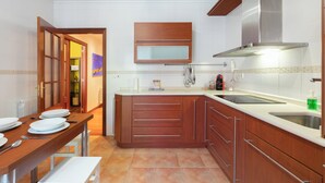 A modern kitchen with wooden cabinets, a built-in oven, and a stainless steel sink.