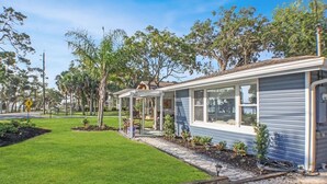 A single-story house with a covered patio, a well-maintained lawn, and a variety of trees. - Riverside Rendezvous, Book Now Your Waterfront Vacation is calling! (Holly Hill)