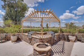 A patio with a stone fire pit, outdoor seating, and a pergola structure. - Golf Views & Pool Access: Central Scottsdale Condo (Scottsdale)