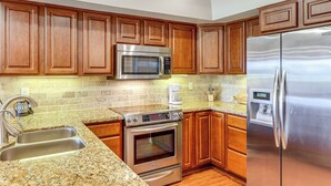 A kitchen with wooden cabinets, a stainless steel refrigerator, a microwave, an oven, and a granite countertop. - Golf Views & Pool Access: Central Scottsdale Condo (Scottsdale)