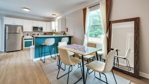 Une cuisine moderne dotée d’un îlot central, de meubles blancs et d’un réfrigérateur en acier inoxydable.