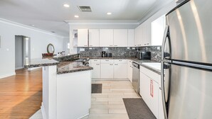 A modern kitchen with white cabinets, granite countertops, a stainless steel refrigerator, and a built-in dishwasher. - 4 Mi to Beaches: Tranquil Fort Lauderdale Escape (Fort Lauderdale)