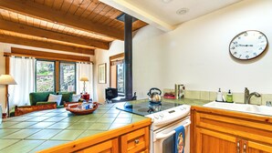 Une cuisine avec des meubles de rangement en bois, une cuisinière, un évier et une grande fenêtre.