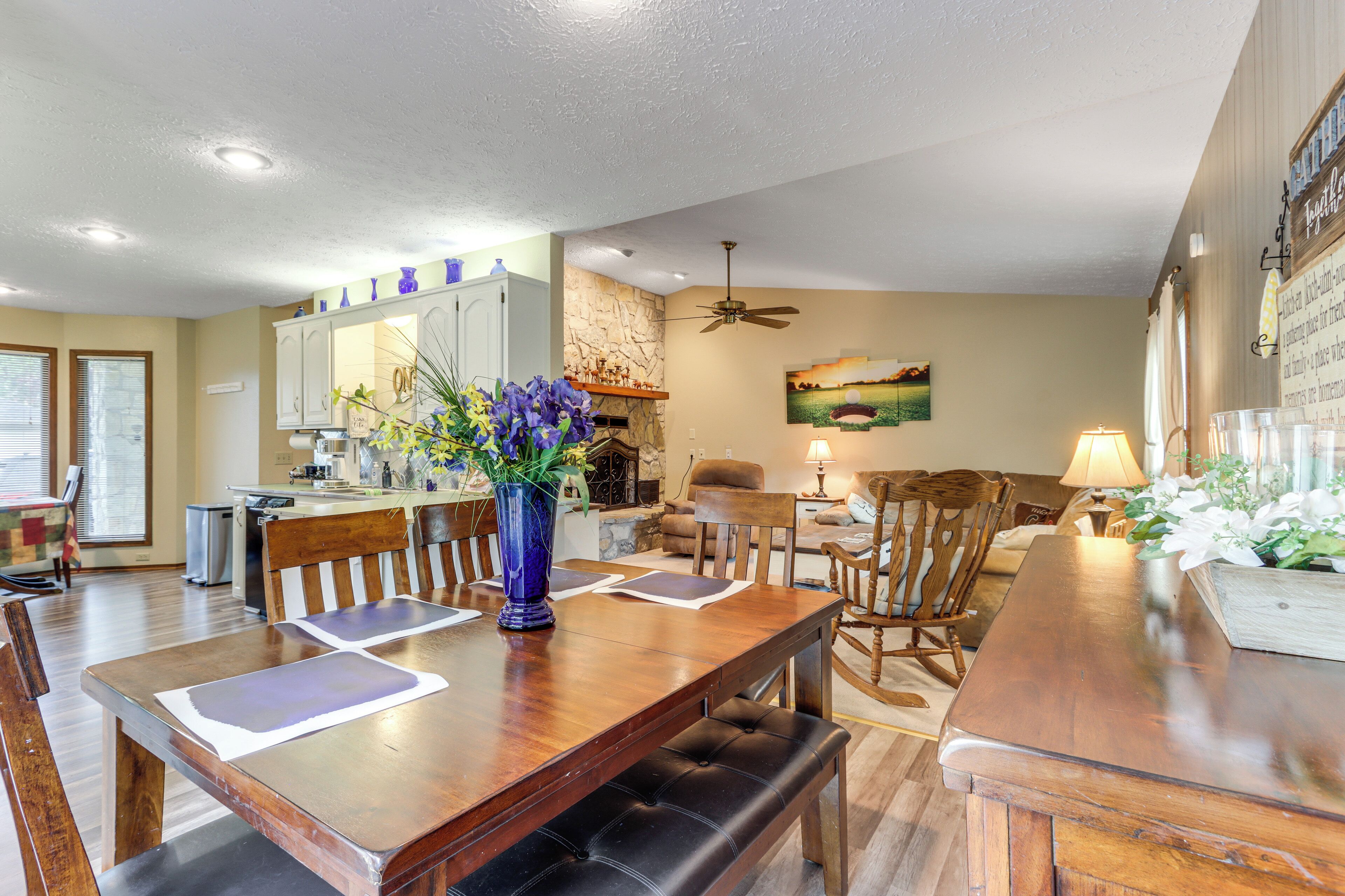 A spacious dining area with a wooden table, chairs, and a vase of flowers.
